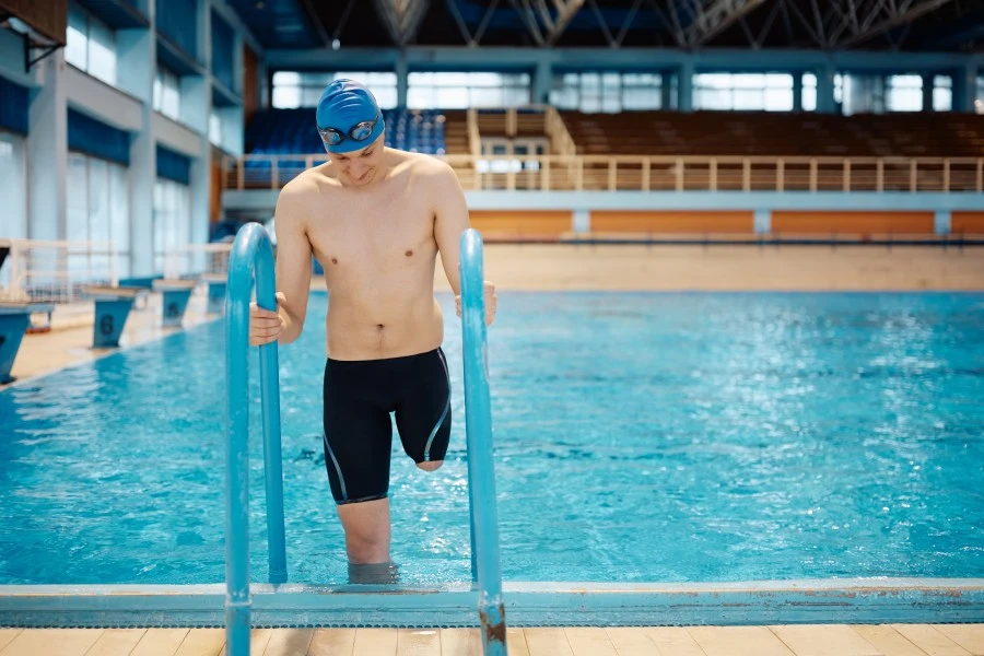 Disabled man climbing out swimming pool via ladder