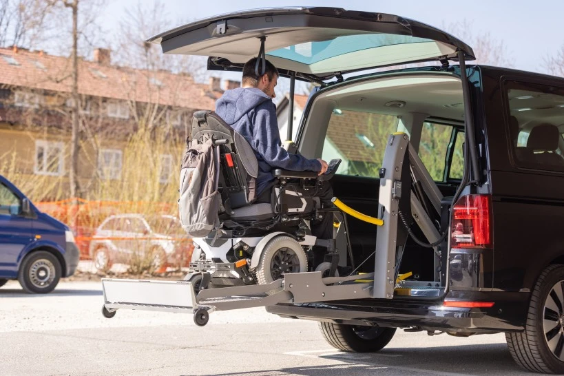 Disabled man in his wheelchair getting inside a van via a lift platform