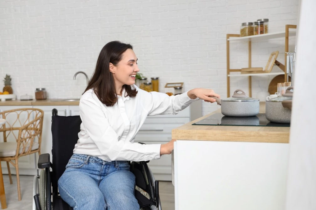 Disabled woman in her wheelchair cooking something in the kitchen