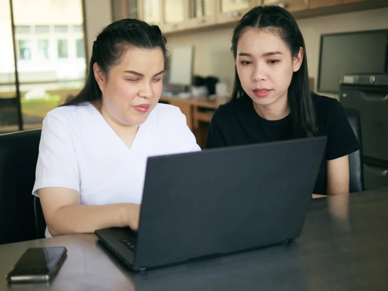 Disabled woman and her support worker looking at a laptop