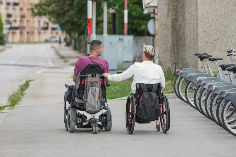 Two disabled people in their wheelchairs along a path