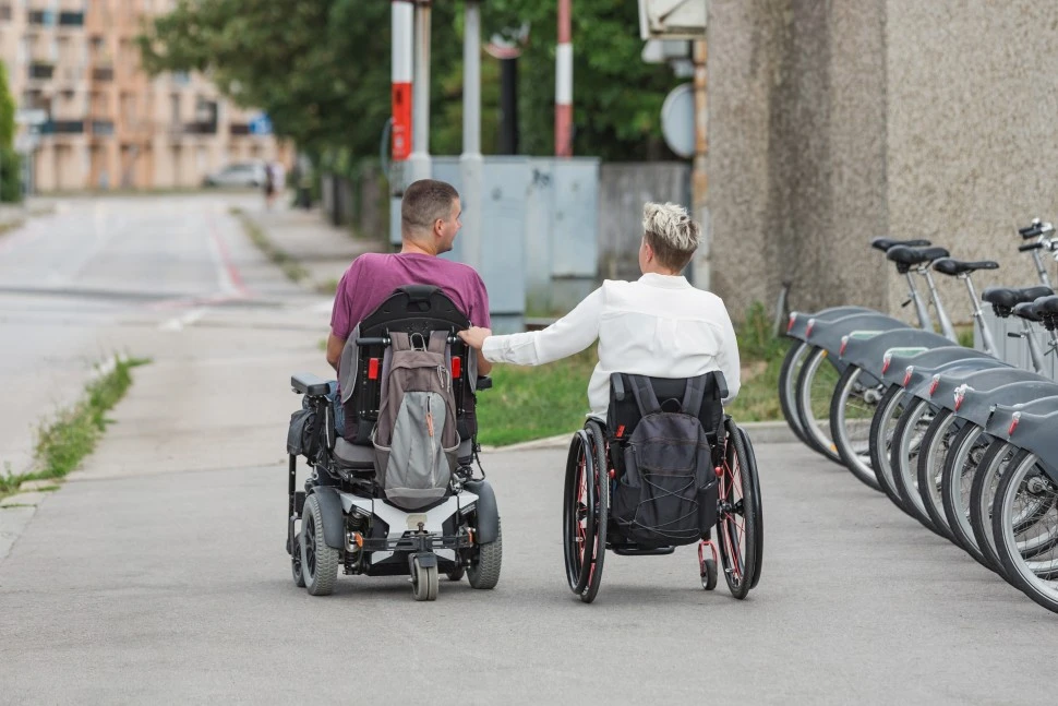Two disabled people in their wheelchairs along a path