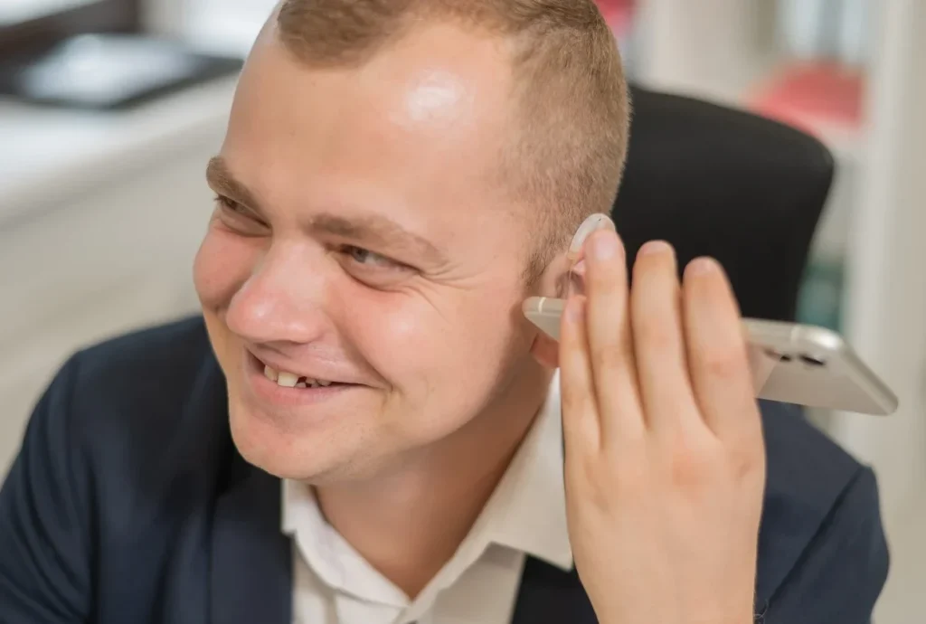 Deaf man listening to something on his phone with the help of his hearing aid